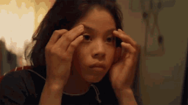 a young girl is looking at herself in a mirror