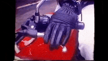 a person is riding a motorcycle with a black glove on .