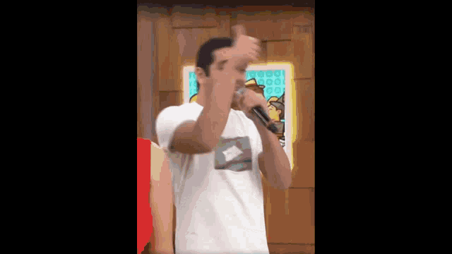 a man singing into a microphone in front of a painting
