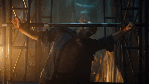 a man in a dark room is holding a metal bar