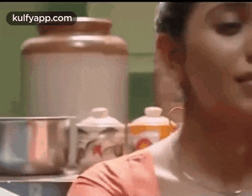 a close up of a woman 's face in a kitchen with a blurred background .