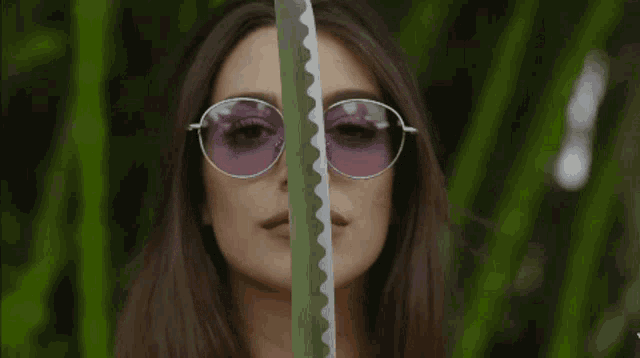 a woman wearing sunglasses and red nails covering her face