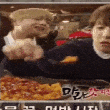 a man is eating a slice of pizza while another man looks on ..
