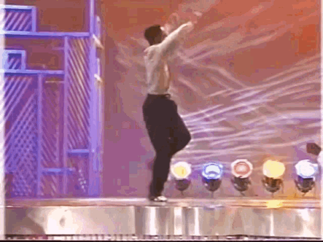a man is dancing on a stage in front of a bunch of lights .