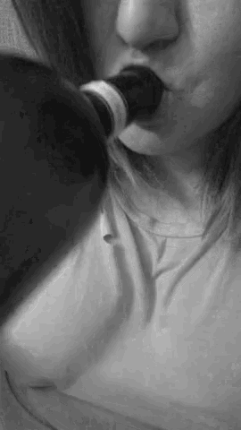 a black and white photo of a woman drinking from a wine bottle