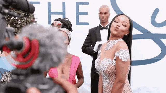 a woman blowing a kiss in front of a sign that says " the "