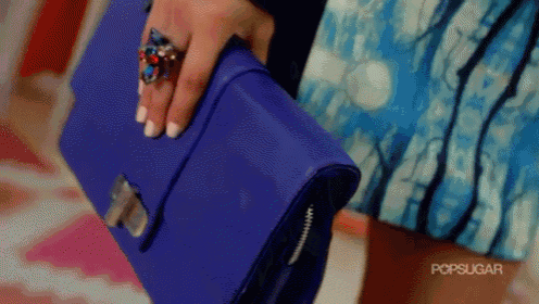 a woman is holding a blue purse with a ring on her finger