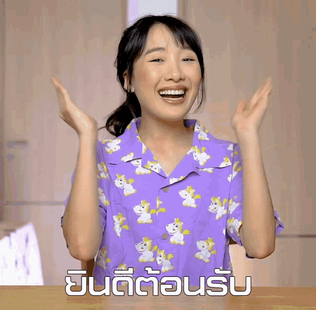 a woman wearing a purple shirt with animals on it is making a gesture