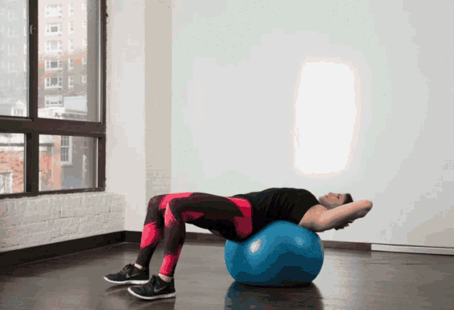 a man laying on a blue exercise ball in a gym