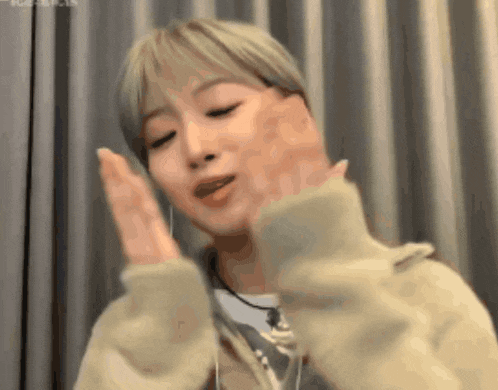 a woman with short blonde hair is making a funny face with her hands .