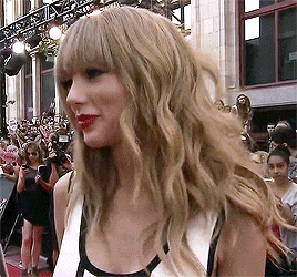 a woman with blonde hair and bangs stands in front of a crowd