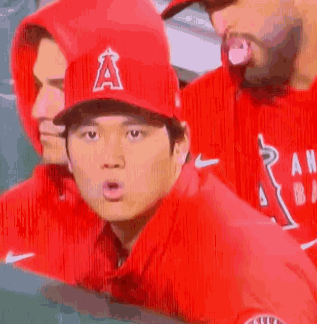 a baseball player wearing a red hat with the letter a on it is sticking out his tongue .