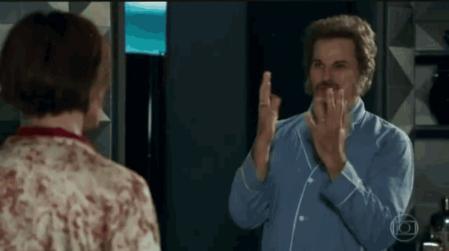 a man in a blue shirt is pointing at a woman in a white shirt