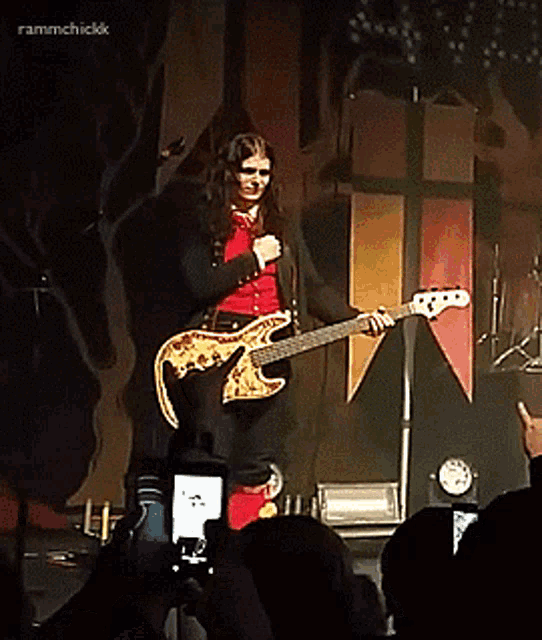 a woman singing into a microphone while holding a guitar in front of a crowd with the hashtag frammchickk above her