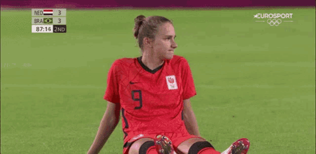 a female soccer player is sitting on the ground during a game