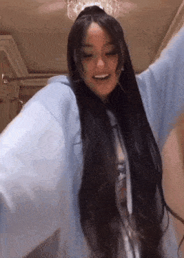 a woman with long hair and a crown on her head is wearing a blue hoodie and dancing .