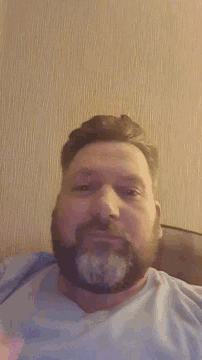 a man with a beard is laying down with his head resting on his hand
