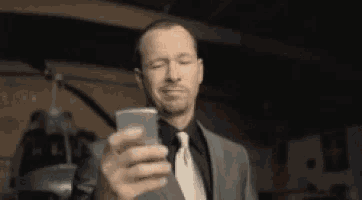 a man in a suit and tie is taking a selfie with his phone .