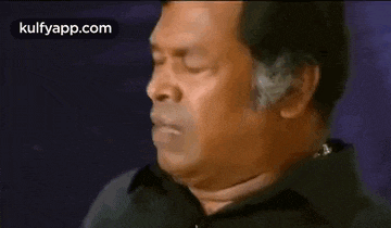 a man in a black shirt is making a funny face with his mouth open .