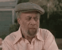 an elderly man with a beard and hat is sitting at a table .