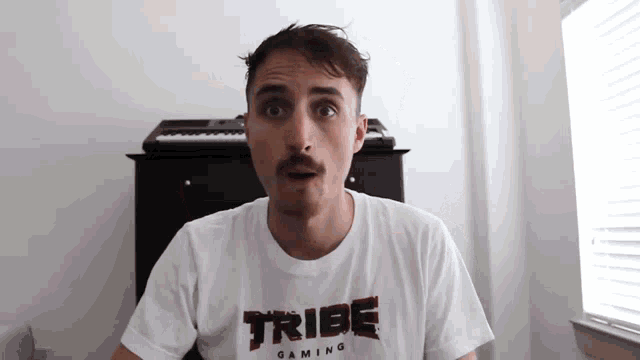 a man with a mustache wearing a tribe gaming shirt