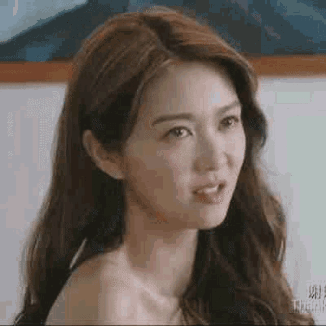 a woman without a shirt is making a funny face while looking at the camera .
