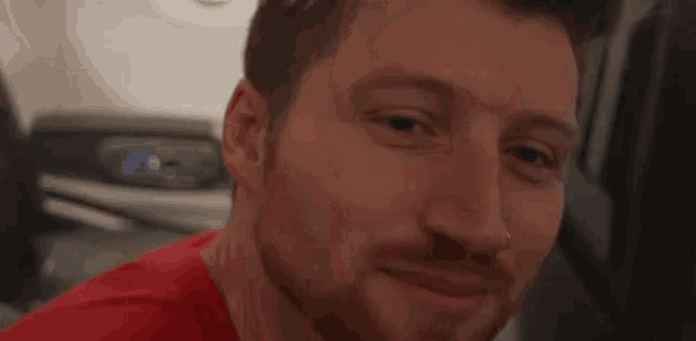 a man in a red shirt is smiling in front of a washing machine