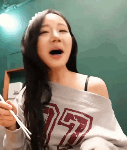 a woman wearing a off the shoulder sweatshirt with the number 157 on it