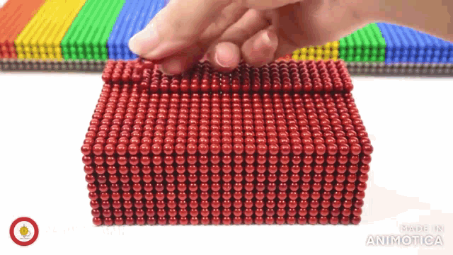a box made of red beads is being opened by a hand
