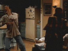 a man is dancing in a living room while a woman looks on