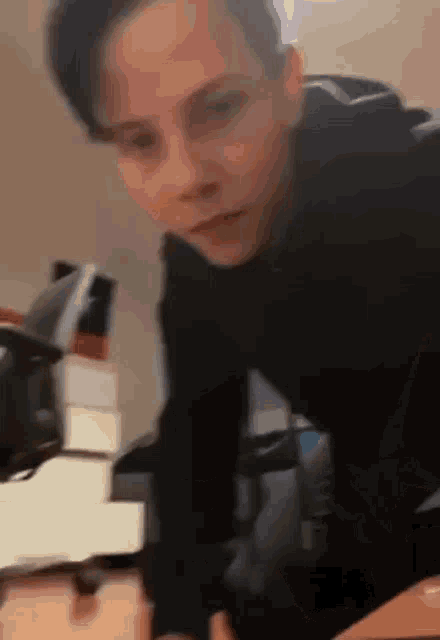 a young boy in a black hoodie is standing in front of a table .