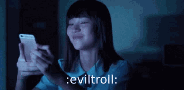 a girl is laughing while looking at her cell phone and the words eviltroll are displayed below her