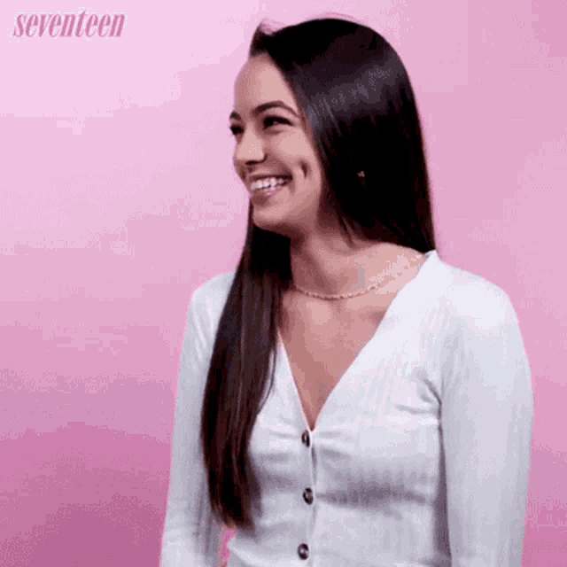 a woman wearing a white cardigan is smiling in front of a pink background that says seventeen