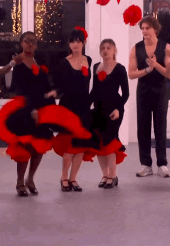 a group of women in red and black dresses are dancing on a dance floor