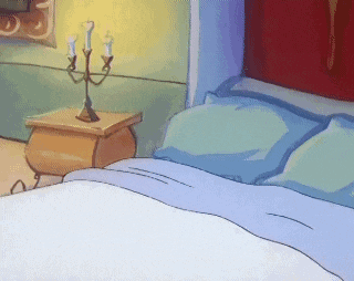 a bed with blue sheets and a nightstand with candles