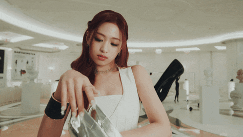 a woman in a white dress is holding a pair of scissors in her hand