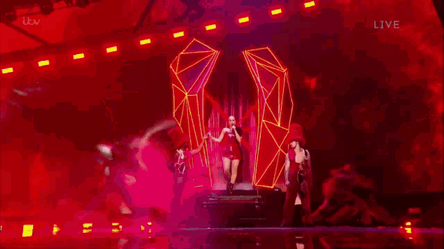 a blurry picture of a woman in a red dress on a stage with itv live in the lower right corner