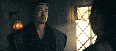 a man in a kimono is talking to a woman in a dark room