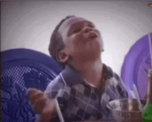 a young boy sitting at a table with a purple plate