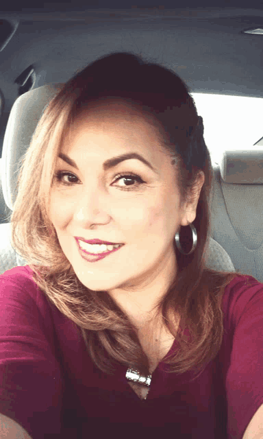 a woman sitting in the back seat of a car smiles for the camera