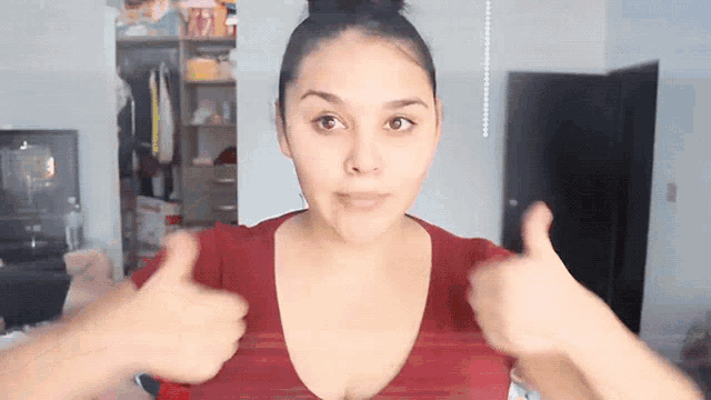 a woman in a red shirt gives a thumbs up