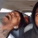 a man is smoking a cigarette in a car while another man looks on .