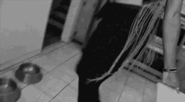 a black and white photo of a person standing next to a couch with a bunch of wires coming out of it .