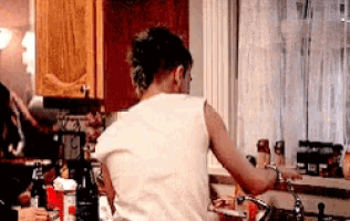 a woman in a white tank top is washing dishes in a kitchen sink