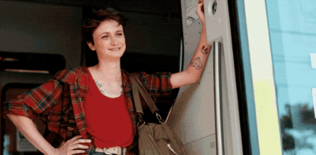 a woman in a plaid shirt has a tattoo on her arm