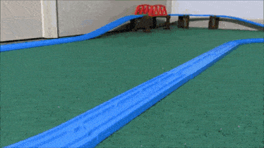 a toy train is going down a track on a green carpet