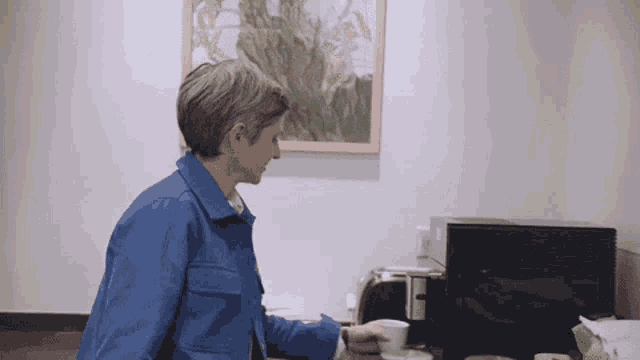 a woman in a blue jacket is reaching for a cup of coffee