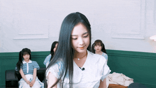 a girl with long black hair is wearing a white shirt and a necklace