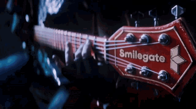 a person is playing a red guitar that says brilligate on the headstock