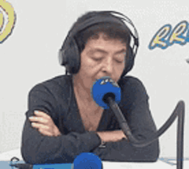 a woman wearing headphones is sitting in front of a microphone with her eyes closed .